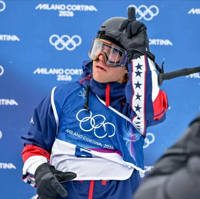 Le fondateur du Real Loser Project de Hunter Hess brandit des pancartes L après avoir participé à la finale masculine de half-pipe aux Jeux olympiques d'hiver de 2026