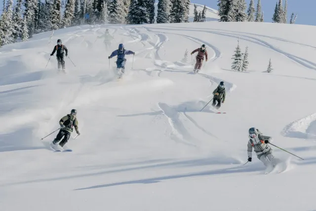 Des amis skient ensemble sur une pente poudreuse.